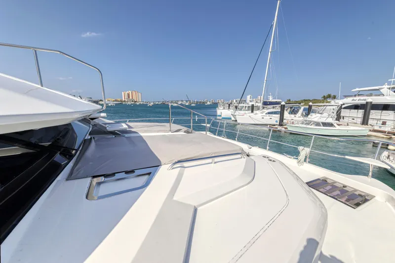  Yacht Photos Pics Aquila 54 Yacht 2023 on water, docked with other boats under clear blue sky.