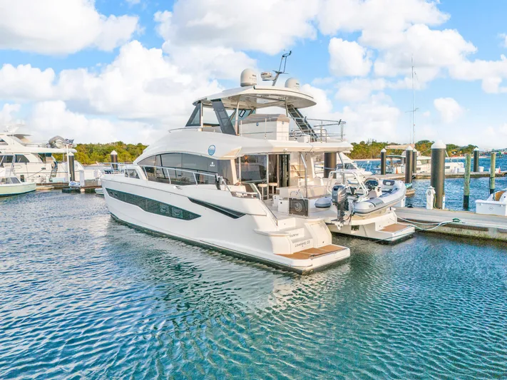  Yacht Photos Pics 2023 Aquila 54 Yacht docked in a marina under a partly cloudy sky.