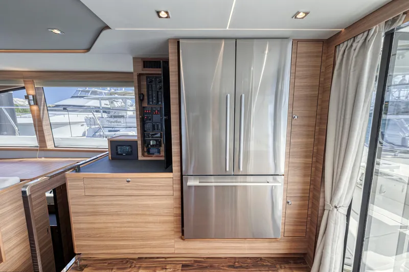  Yacht Photos Pics Modern kitchen interior of 2023 Aquila 54 Yacht with stainless steel appliances and wood paneling.