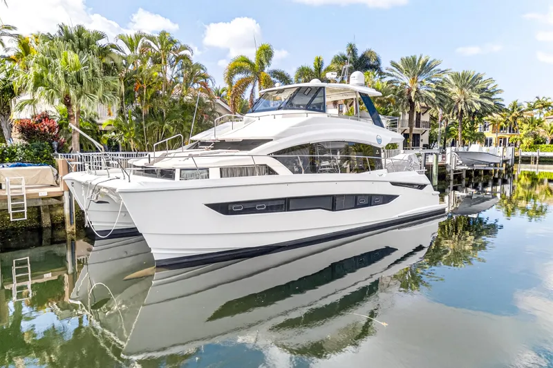  Yacht Photos Pics 2023 Aquila 54 Yacht docked in a tropical marina setting.