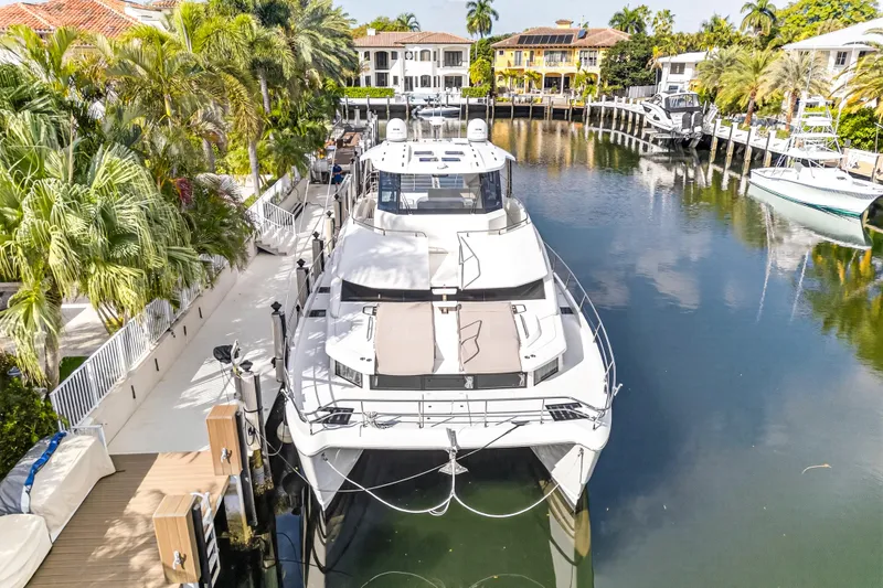  Yacht Photos Pics 2023 Aquila 54 Yacht docked in a scenic waterfront setting with palm trees.