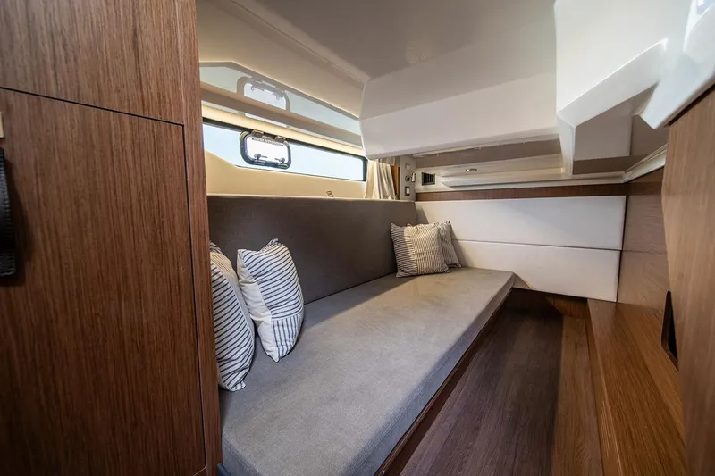  Yacht Photos Pics Manufacturer Provided Image: 2026 Beneteau Antares 12 Coupe interior with cozy seating and striped cushions.