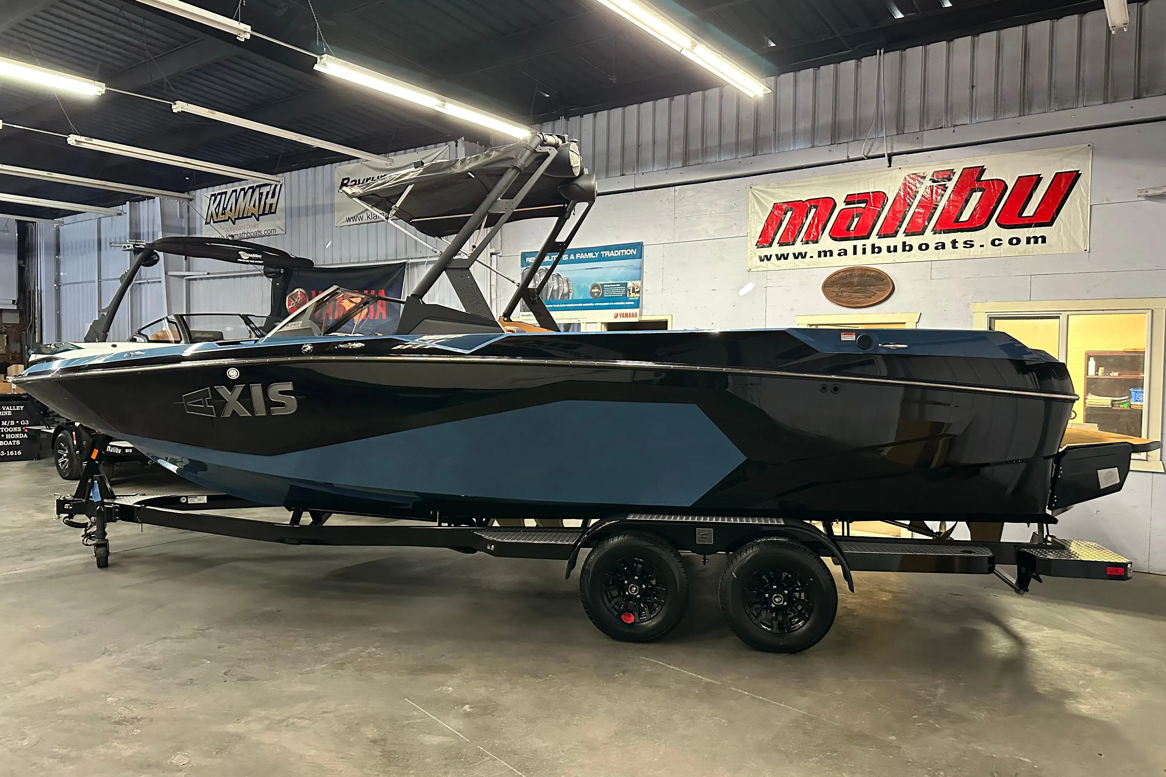 2025 Axis A245 boat in showroom, black and blue design, on trailer.
