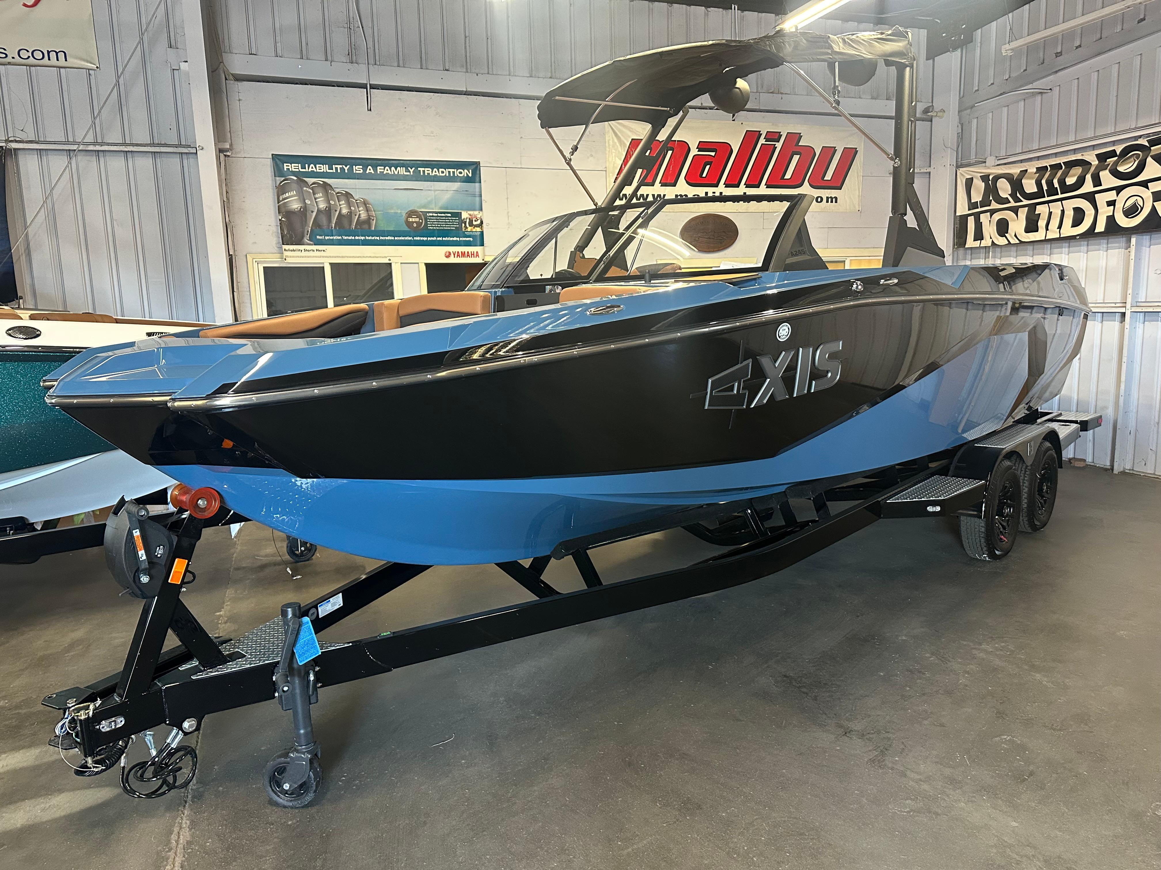 2025 Axis A245 boat in showroom, black and blue design, on trailer.