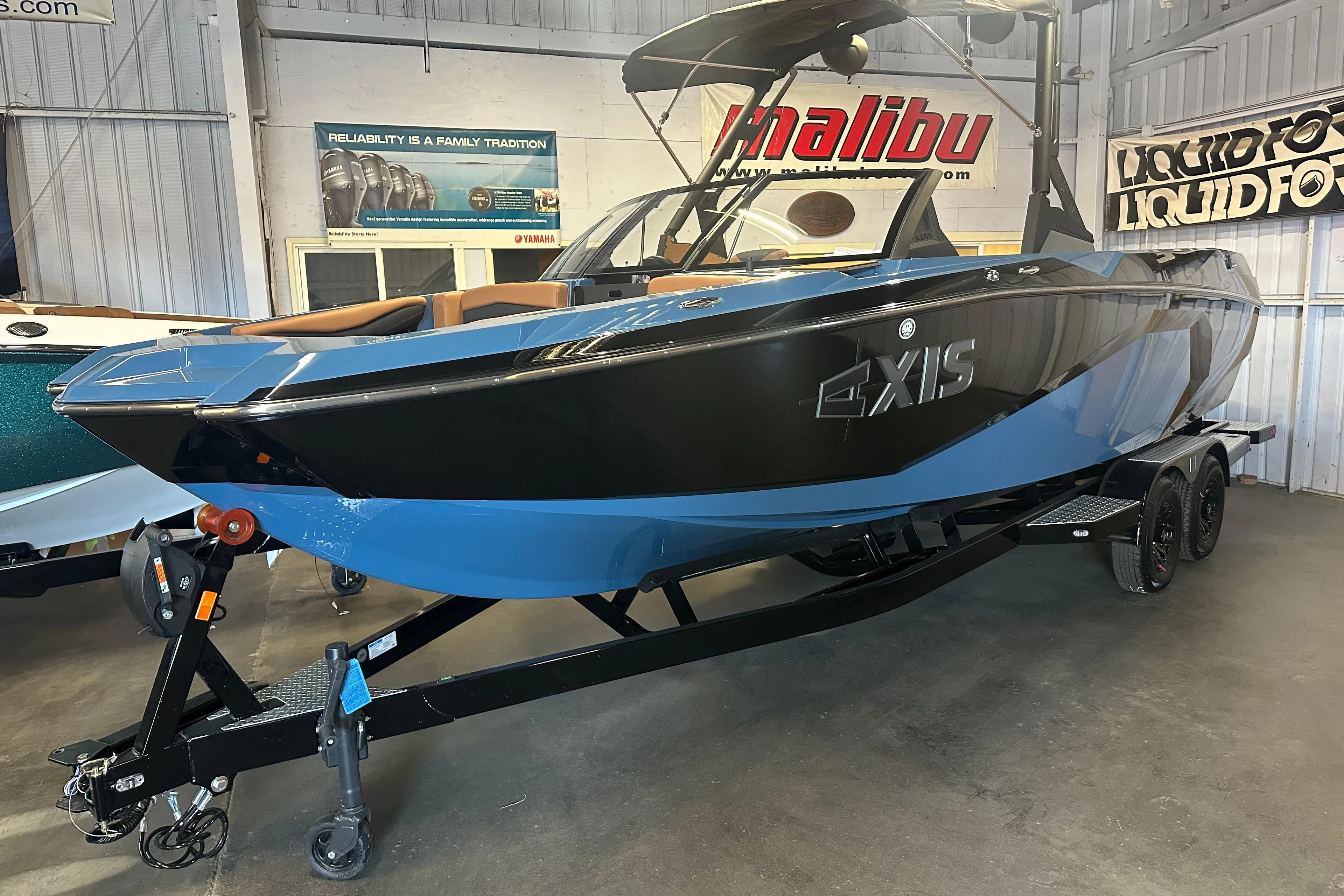 2025 Axis A245 boat in showroom, black and blue design, on trailer.