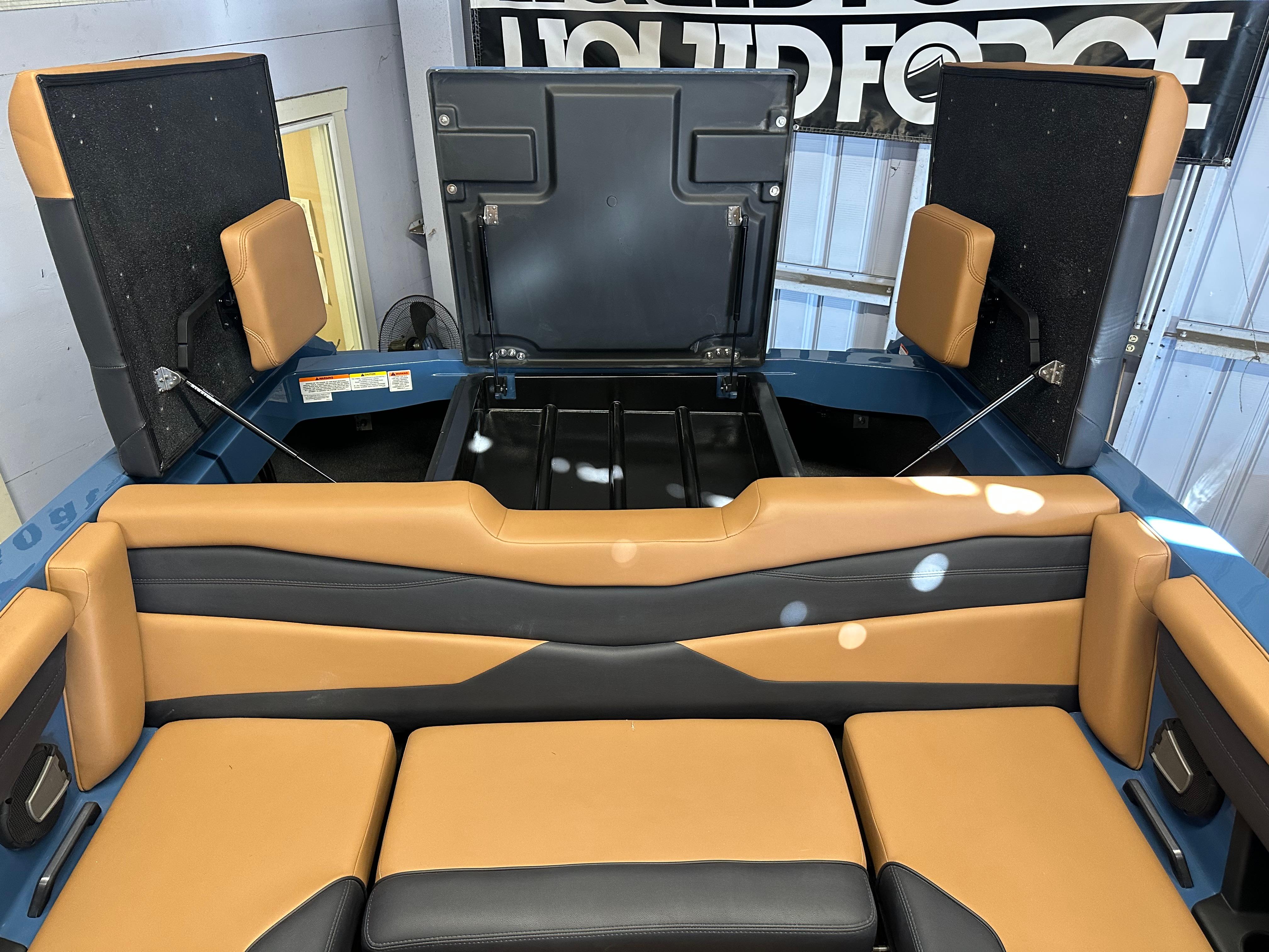 2025 Axis A245 boat interior with tan and black seating, open storage compartments.