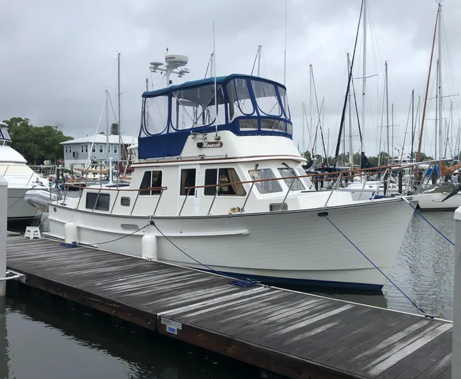 Monarch Yacht Photos Pics 1997 Monk 36 boat docked at marina, featuring blue canopy and classic design.