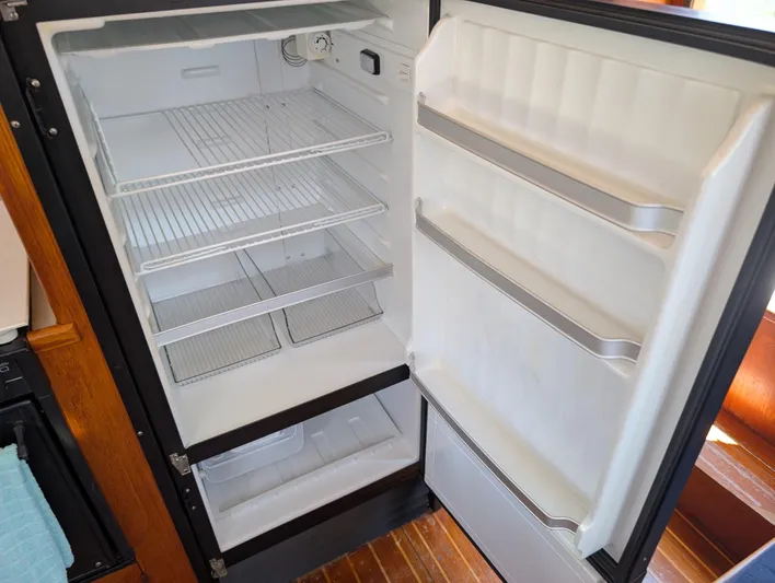 Monarch Yacht Photos Pics Empty refrigerator with open door, featuring wire shelves and door compartments, inside a 1997 Monk 36.