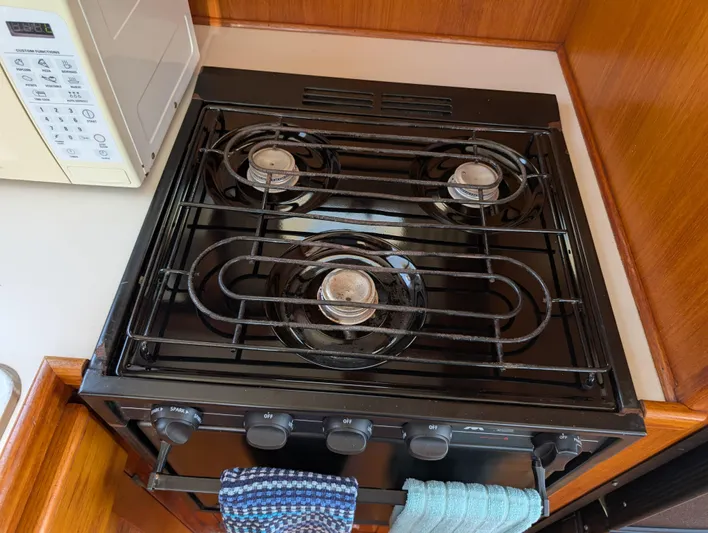 Monarch Yacht Photos Pics Gas stove with three burners in a wooden kitchen, featuring a microwave. Monk 36, 1997 model.