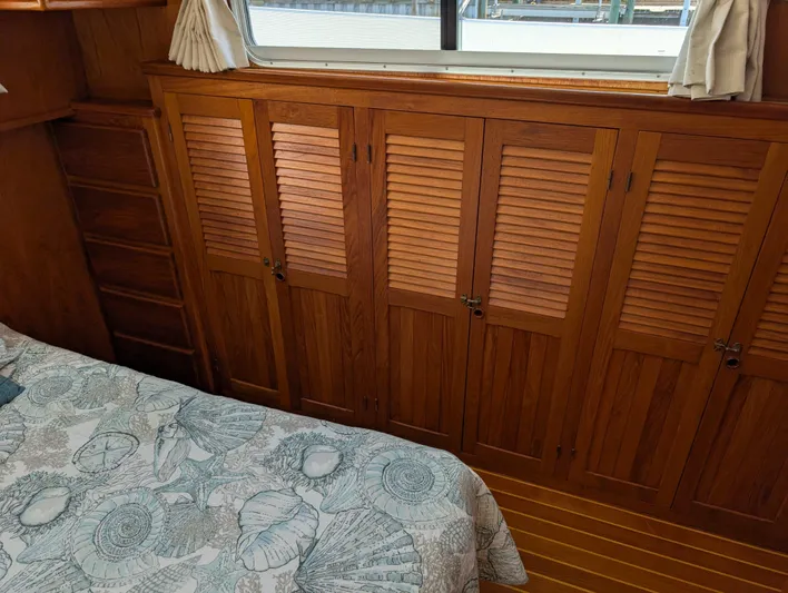 Monarch Yacht Photos Pics Wood-paneled cabin interior of 1997 Monk 36 boat with louvered closets and patterned bedding.
