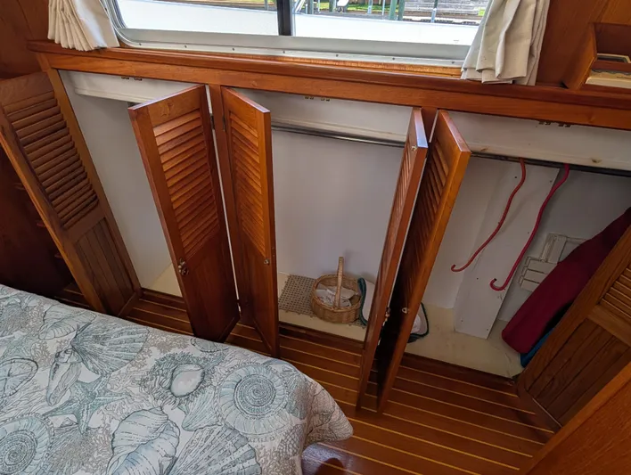 Monarch Yacht Photos Pics Wooden interior of a 1997 Monk 36 boat with open closet and patterned bedding.