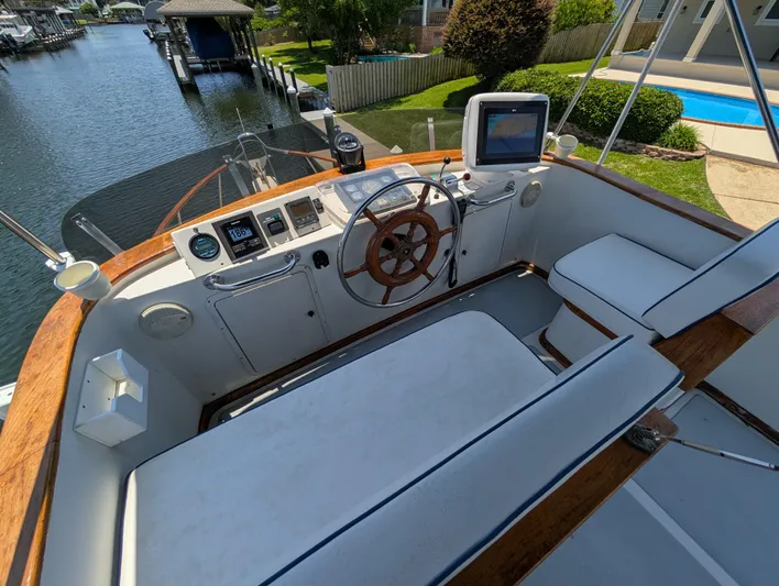 Monarch Yacht Photos Pics 1997 Monk 36 boat helm with wooden wheel, modern controls, and seating by a canal.