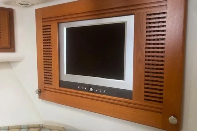 Miss Madison Yacht Photos Pics Built-in TV on 2003 Cabo 35 Express yacht, framed in wood paneling.