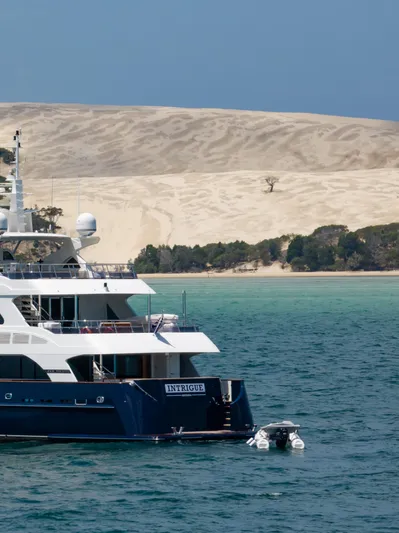 Intrigue Yacht Photos Pics Luxury Jade 95 Motor Yacht (2010) anchored near sandy dunes and turquoise waters.