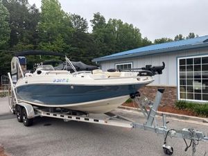 2021 Stingray 212 SC boat on trailer, parked near a building with trees in the background.