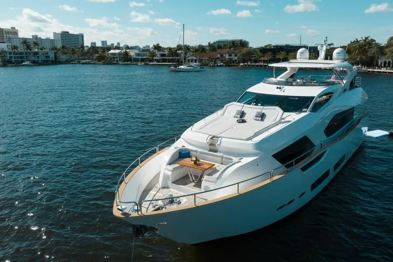 Mirracle Yacht Photos Pics Luxurious 2018 Sunseeker 95 Yacht on serene water with cityscape backdrop.