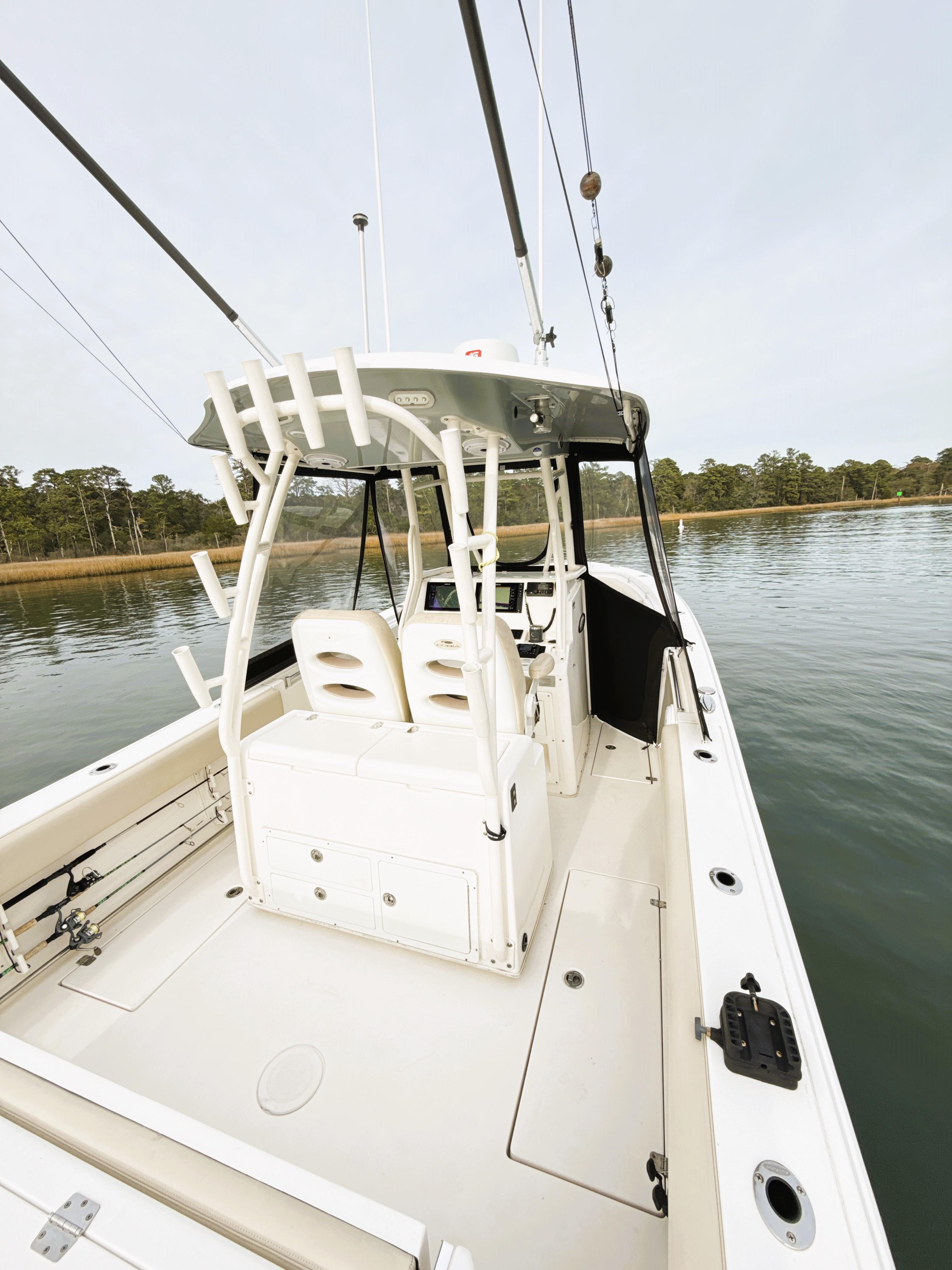 2016 Cobia 296 Center Console boat on calm water, featuring spacious deck and seating.