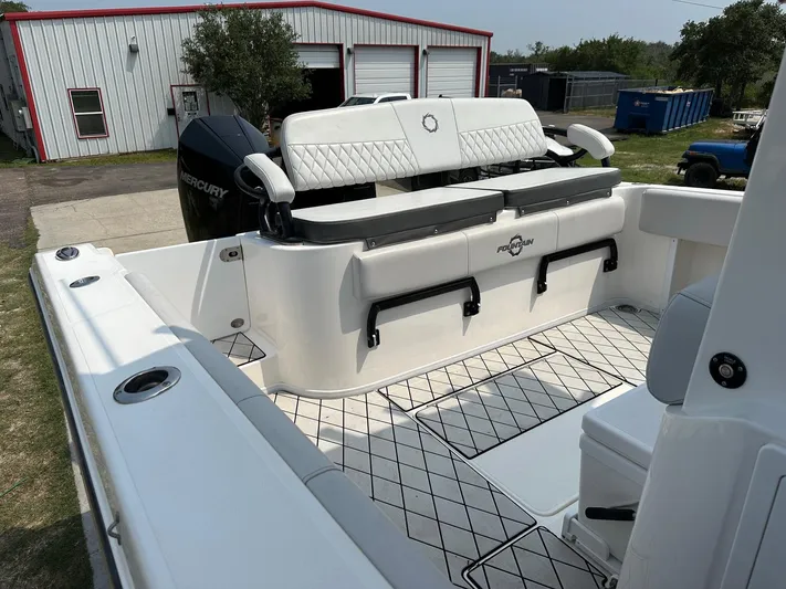  Yacht Photos Pics 2021 Fountain 34TE boat with spacious seating and Mercury engine, parked near a warehouse.