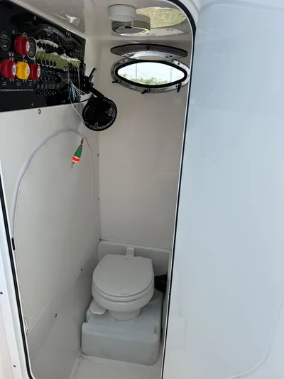 Yacht Photos Pics 2021 Fountain 34TE boat interior with compact marine toilet and control panel.