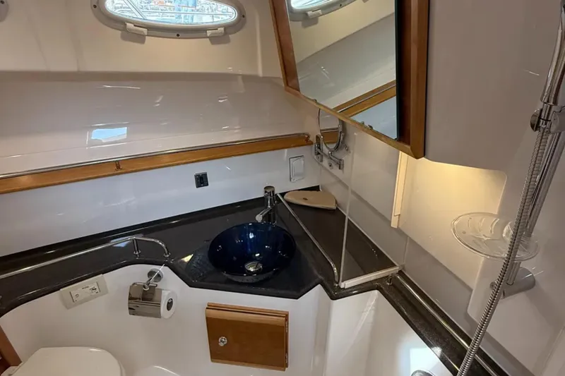  Yacht Photos Pics 2021 Cutwater C-32 Coupe bathroom with modern sink, mirror, and porthole window.
