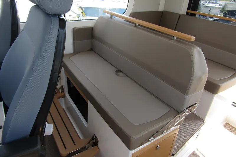  Yacht Photos Pics Interior seating of 2025 Nimbus Commuter 11 boat, featuring comfortable gray upholstery.