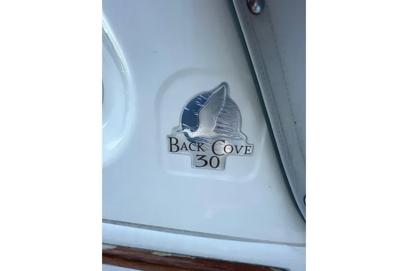 Old Fashioned (reserved) Yacht Photos Pics Emblem of Back Cove 30 boat, featuring a sailboat design on a white surface.