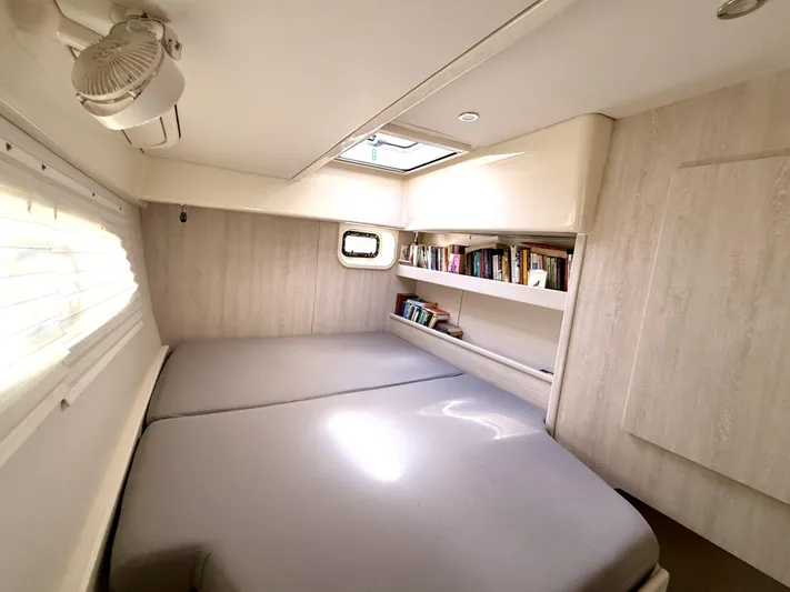 Diastema Yacht Photos Pics Cozy cabin interior of 2016 Leopard 44 yacht with bed, fan, and bookshelf.