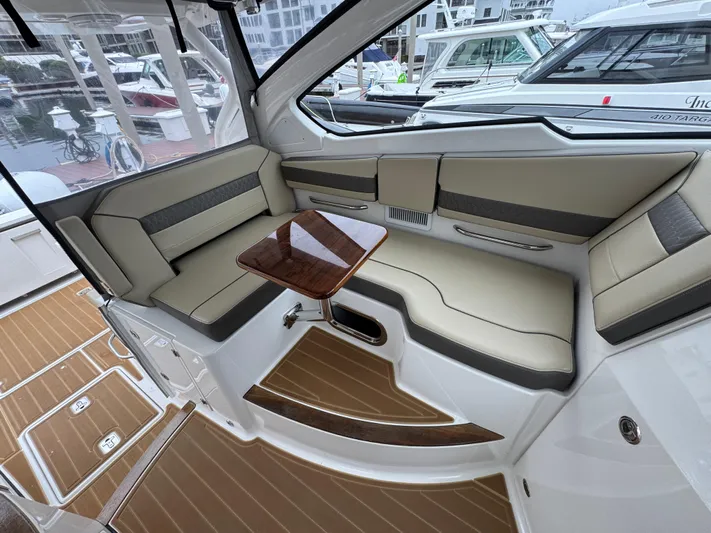  Yacht Photos Pics 2019 Pursuit DC 365 Dual Console interior with beige seating and wooden table.