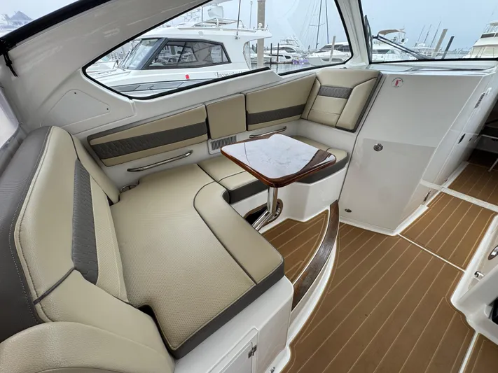  Yacht Photos Pics 2019 Pursuit DC 365 Dual Console interior with beige seating and wooden table.
