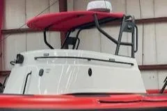  Yacht Photos Pics 2025 Fluid Watercraft 26 SAR boat with red canopy in a warehouse setting.