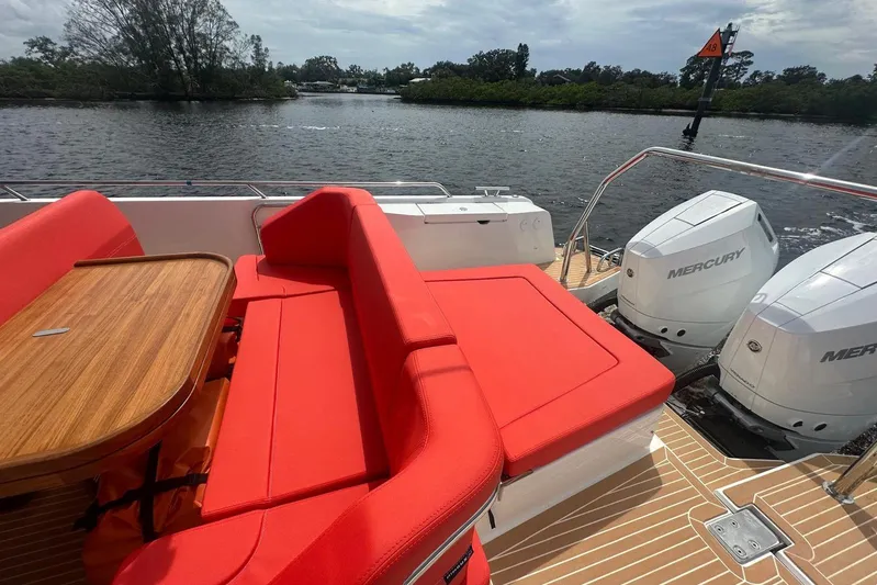  Yacht Photos Pics 2025 Nimbus Tender 11 with red seating, wooden table, and dual Mercury engines on a sunny day.