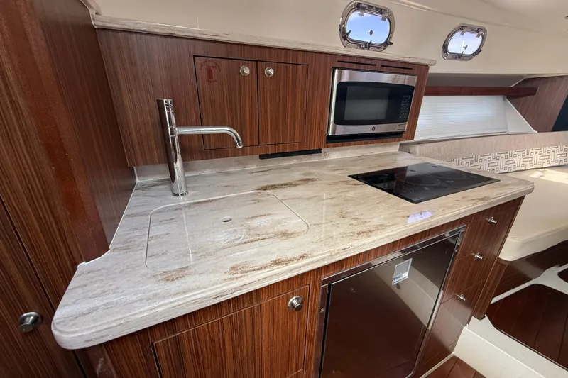  Yacht Photos Pics 2022 Pursuit OS 355 Offshore yacht kitchen with wood cabinetry and modern appliances.