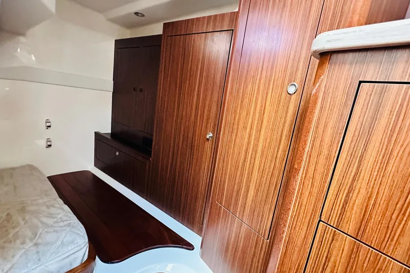 Yacht Photos Pics 2022 Pursuit OS 355 Offshore cabin interior with wood paneling and bed.