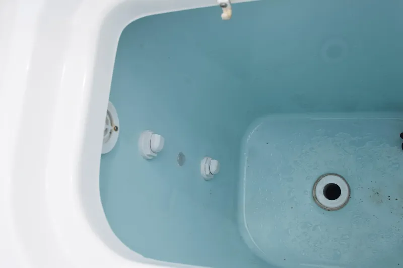  Yacht Photos Pics Livewell interior of 2022 Pursuit OS 355 Offshore boat, featuring drain and fittings.