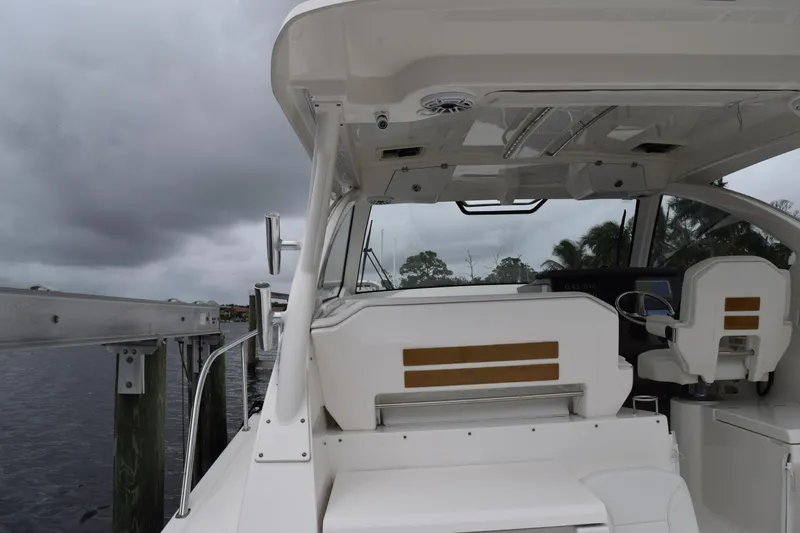  Yacht Photos Pics 2022 Pursuit OS 355 Offshore boat interior with helm and seating, docked under cloudy skies.