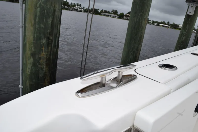  Yacht Photos Pics 2022 Pursuit OS 355 Offshore boat docked by wooden pilings on a cloudy day.