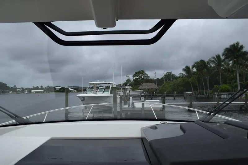  Yacht Photos Pics 2022 Pursuit OS 355 Offshore boat docked at marina, overcast sky, palm trees in background.