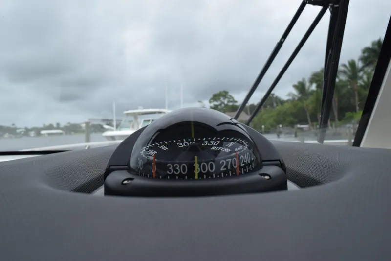  Yacht Photos Pics Compass on 2022 Pursuit OS 355 Offshore boat dashboard, with cloudy sky and marina view.