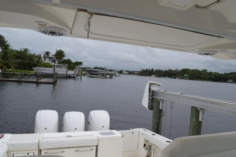  Yacht Photos Pics 2022 Pursuit OS 355 Offshore boat docked by a scenic waterfront with lush greenery.