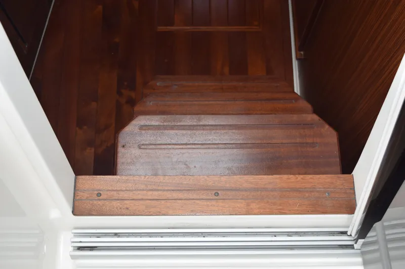  Yacht Photos Pics Wooden steps inside a 2022 Pursuit OS 355 Offshore boat, showcasing elegant craftsmanship.