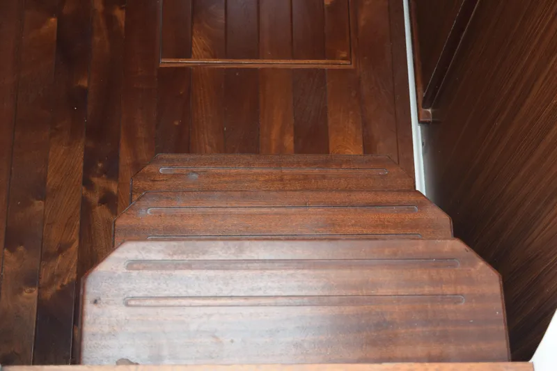  Yacht Photos Pics Wooden steps inside a 2022 Pursuit OS 355 Offshore boat, showcasing rich brown finish.