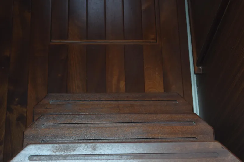  Yacht Photos Pics Wooden steps inside a 2022 Pursuit OS 355 Offshore boat, showcasing elegant craftsmanship.