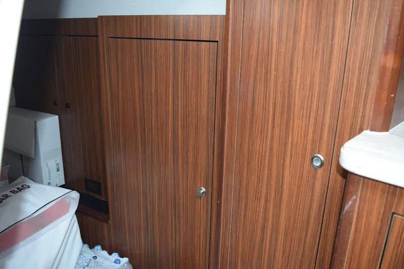  Yacht Photos Pics 2022 Pursuit OS 355 Offshore cabin interior with wooden cabinetry and storage.
