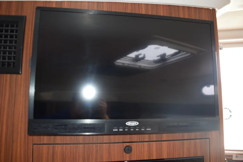  Yacht Photos Pics Flat-screen TV inside 2022 Pursuit OS 355 Offshore boat, mounted on wood paneling.