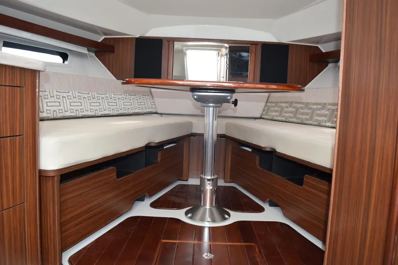  Yacht Photos Pics 2022 Pursuit OS 355 Offshore cabin interior with wood finish and cushioned seating.