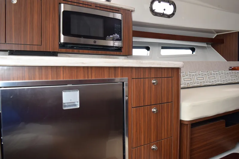  Yacht Photos Pics 2022 Pursuit OS 355 Offshore interior with microwave, fridge, and seating area.