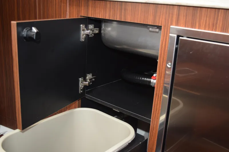  Yacht Photos Pics 2022 Pursuit OS 355 Offshore interior cabinet with open door and visible plumbing.