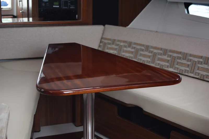  Yacht Photos Pics Interior of 2022 Pursuit OS 355 Offshore with polished wooden table and cushioned seating.
