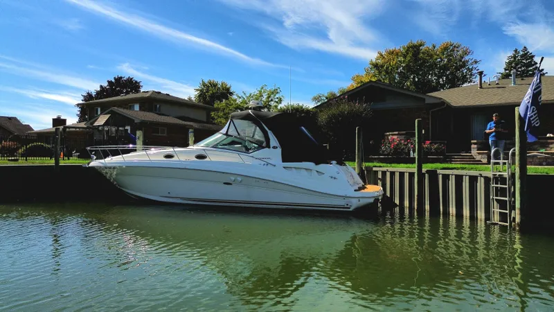  Yacht Photos Pics 2003 Sea Ray 340 Sundancer docked by waterfront homes under a clear blue sky.