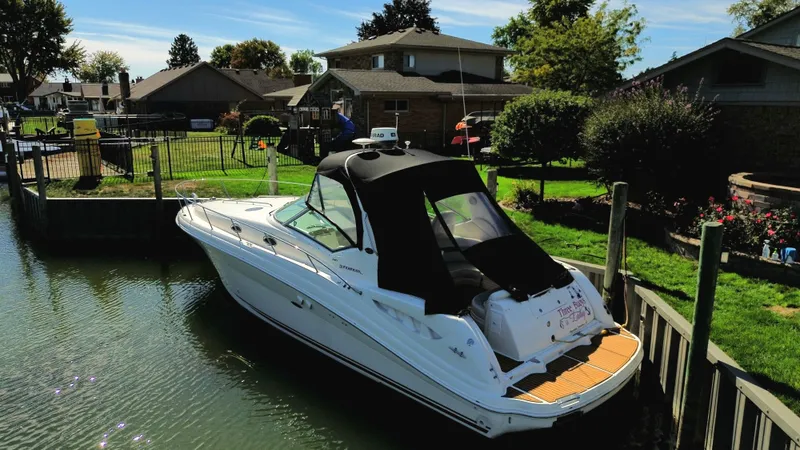  Yacht Photos Pics 2003 Sea Ray 340 Sundancer docked by a residential canal, surrounded by greenery and houses.